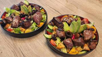 Two bowls of salad with grilled meat, avocado, and vegetables.
