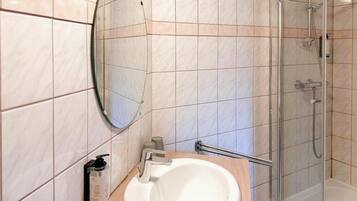 Une salle de bain avec un lavabo, un miroir et une douche.