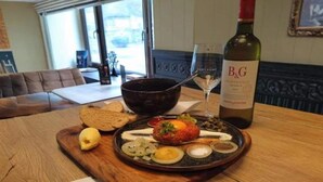 Une table à manger avec une assiette de nourriture, une bouteille de vin et un verre.