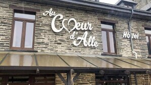 Un bâtiment à la façade en pierre, sur lequel on peut lire l’inscription « Au Cœur d’Alle ».