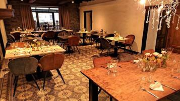 Un restaurant doté de nombreuses tables dressées pour le service, avec un sol à motifs et des meubles en bois.