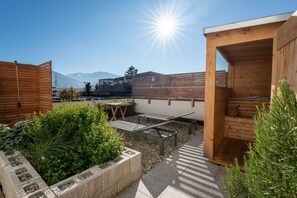 Un jardín en la azotea con estructuras de madera, una mesa y un banco.