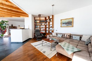 A spacious living area with a large sofa, a coffee table, and a bookshelf.
