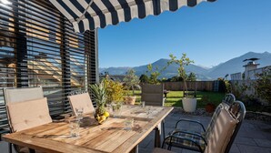 An outdoor patio with a wooden table, chairs, and a striped awning. - Chalet Innerwald (Gnadenwald)