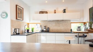 A modern kitchen with white cabinets, a brick backsplash, and a wooden countertop. - Chalet Innerwald (Gnadenwald)