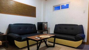 Un petit salon avec deux canapés, une table basse et un téléviseur.