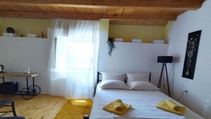 A bedroom with a bed, a desk, a chair, a lamp, and a window with curtains.