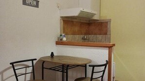 A small kitchenette with a wooden countertop, two chairs, and a sign that reads "OPEN".