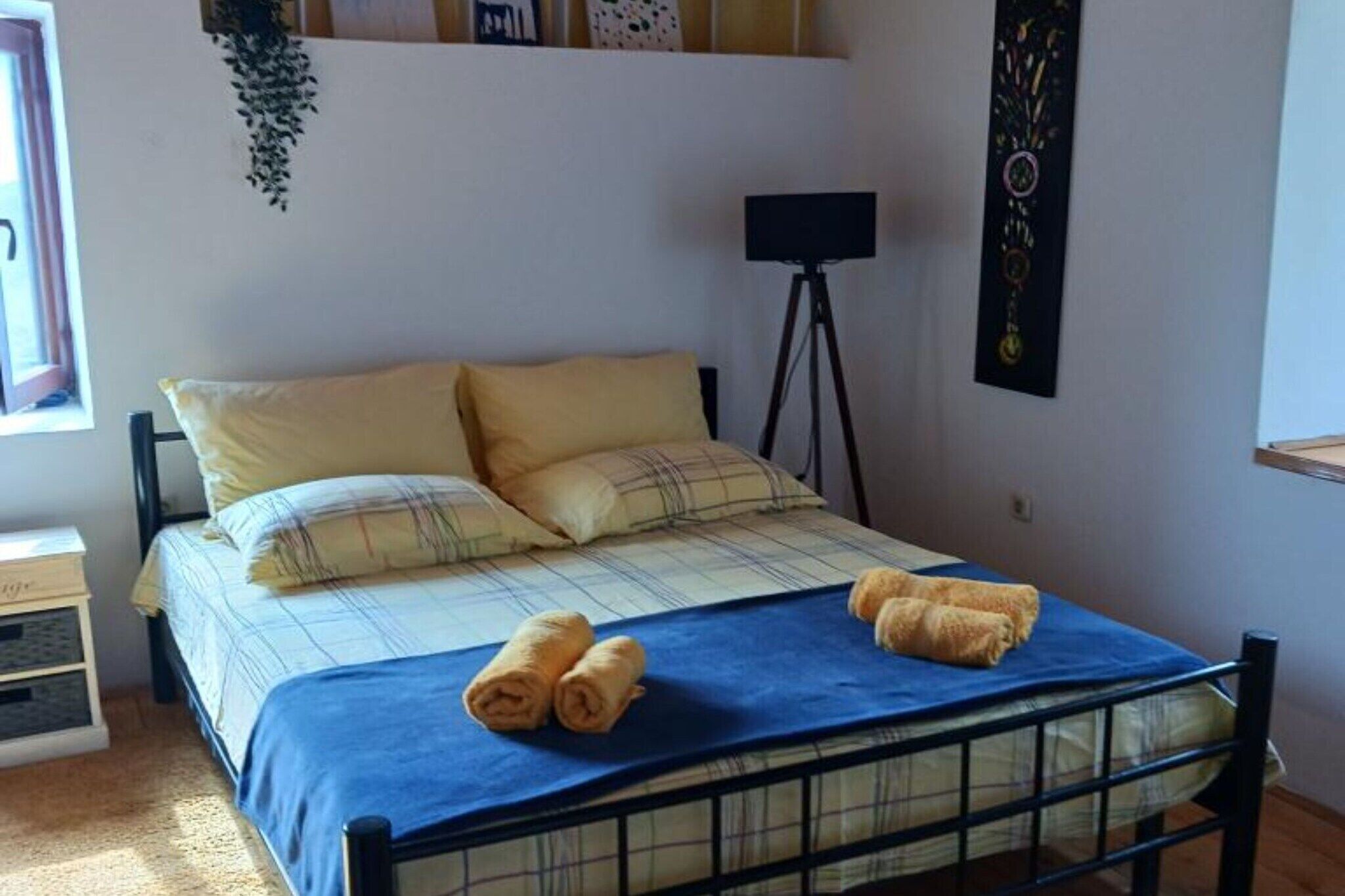 Un lit bien fait, recouvert d’une couverture à carreaux, avec deux oreillers et deux serviettes enroulées posées sur le lit.