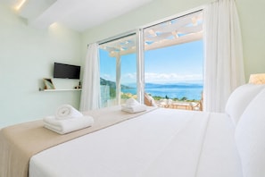 Ein Hotelzimmer mit Bett, Fernseher, Meerblick und Balkon mit Stühlen.
