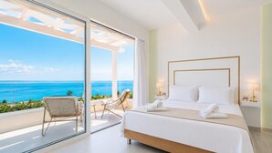A bedroom with a large bed, a view of the ocean, and a balcony with chairs. - Villa Aglaia in Mparmpati (Corfu)