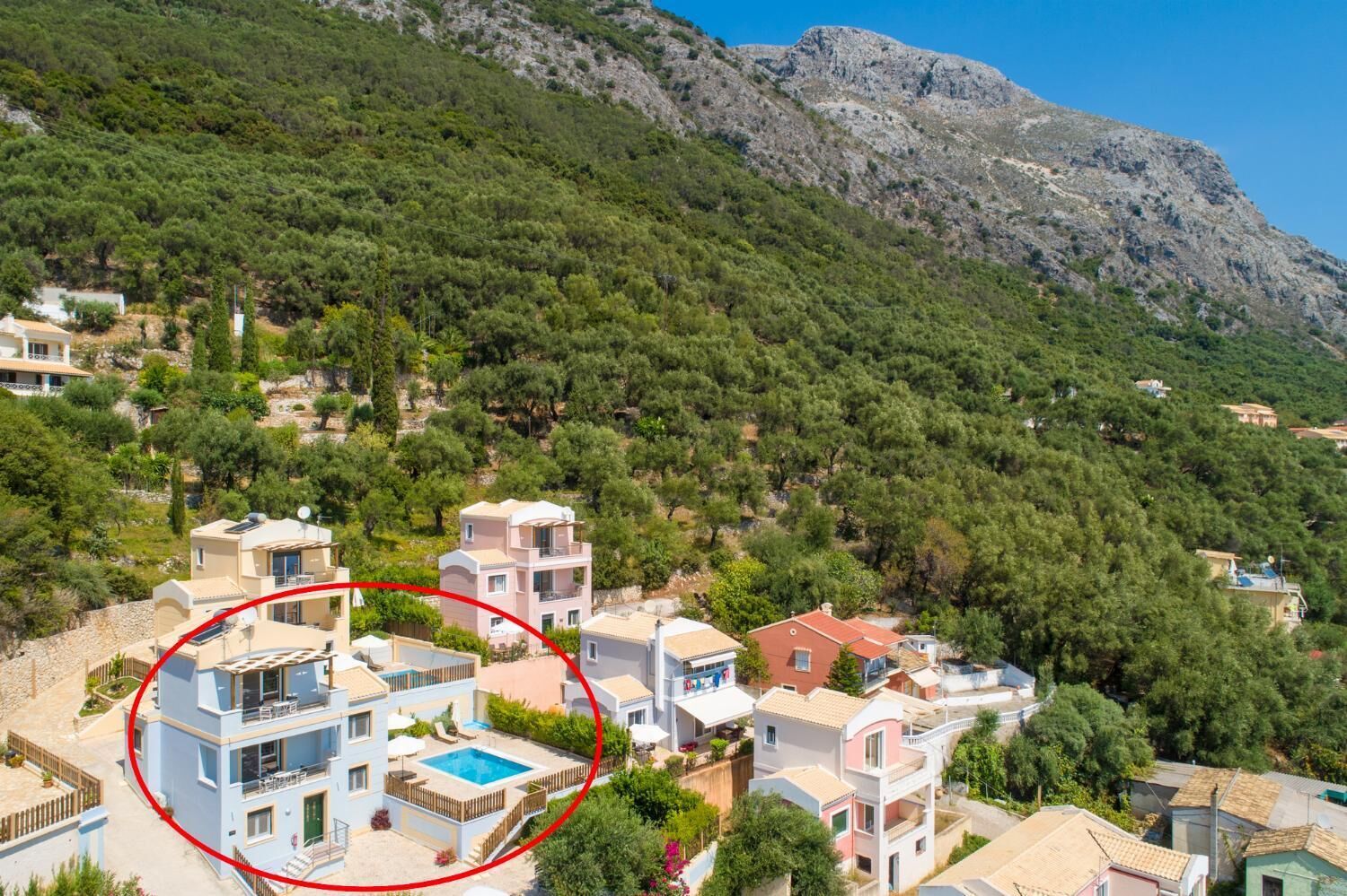 A residential area with modern houses, a swimming pool, and a mountainous backdrop.