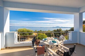 A balcony with a table set for dining, overlooking a scenic view of the sea and distant mountains. - Villa Alya View in Mparmpati (Corfu)