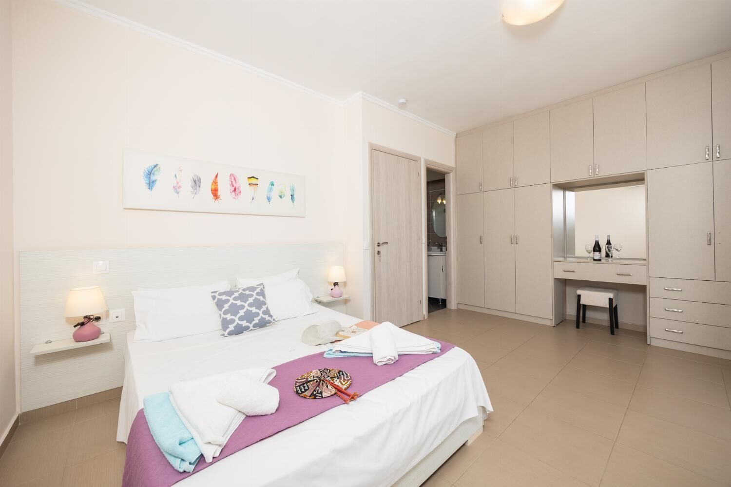 A bedroom with a bed, bedside tables, a desk, and a wardrobe.