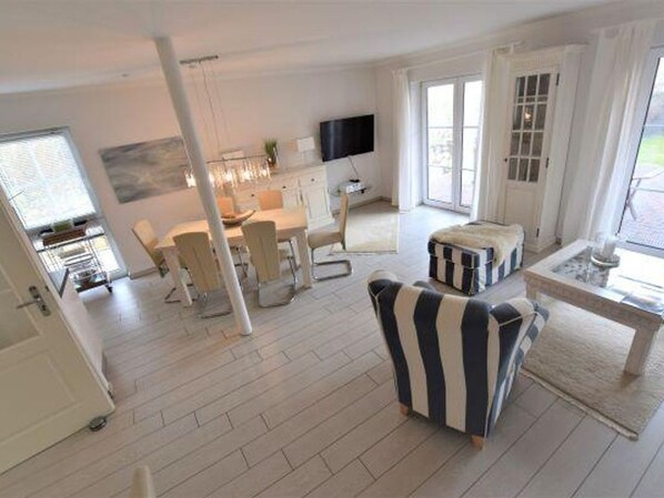 A spacious living area with a dining table, chairs, and a television.
