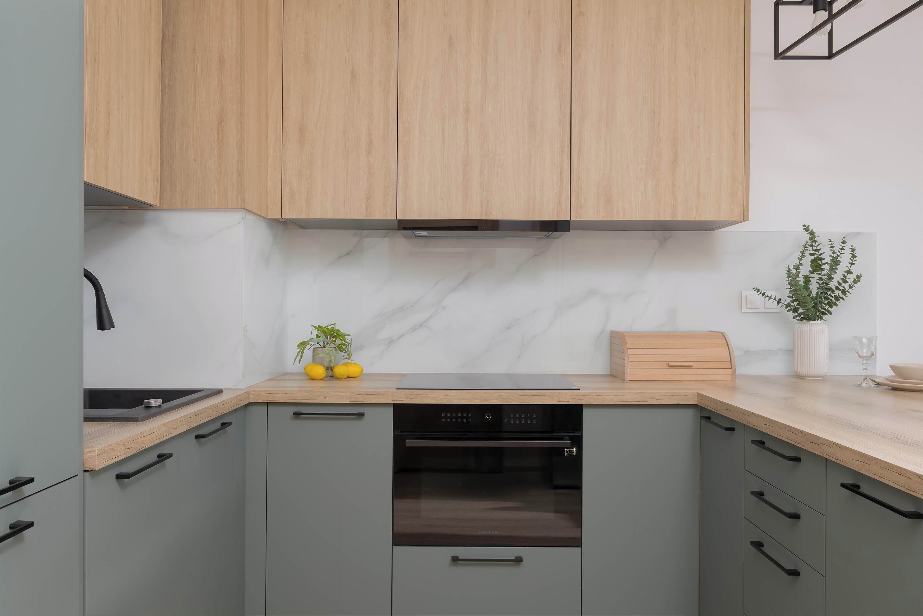 Una cocina moderna con armarios grises, encimera de madera y horno empotrado.