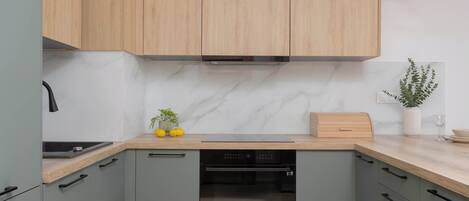 Una cocina moderna con armarios grises, encimera de madera y horno empotrado.