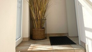 A hallway with a potted plant, a door, and a window. - Due/05a - Im Dünengrund App. 05a (Sylt)