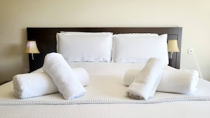 Un lit bien fait, avec du linge de lit blanc et des oreillers, deux lampes de chevet et une simple tête de lit.