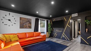 Ein modernes Wohnzimmer mit einer Couch, einer Uhr und einem Fernseher.