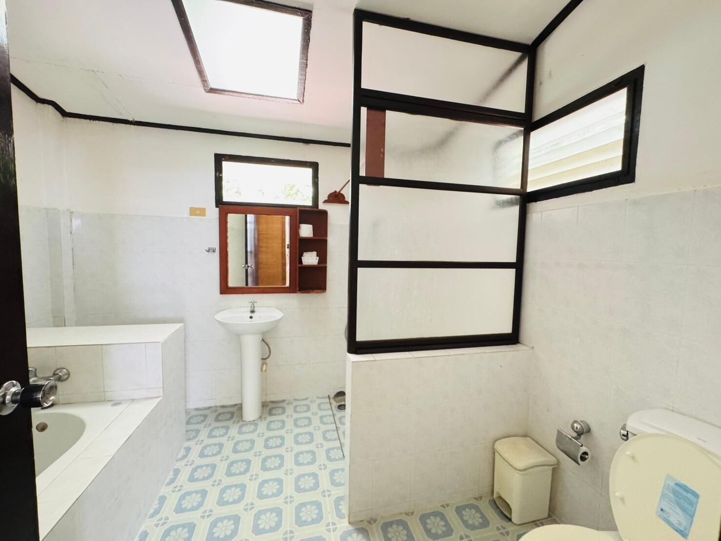 Un baño con lavabo, espejo, inodoro y baldosas de suelo estampadas.