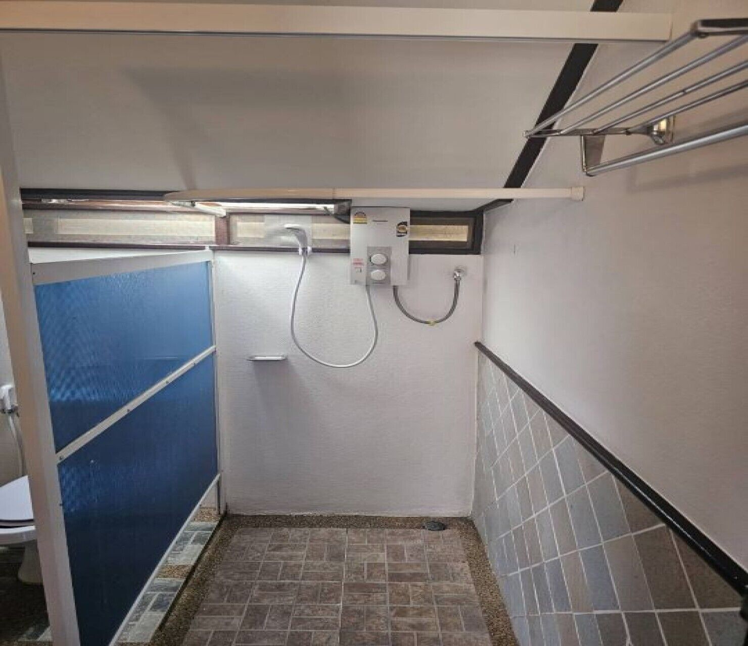 A small, enclosed bathroom with a shower, a toilet, and a sink.