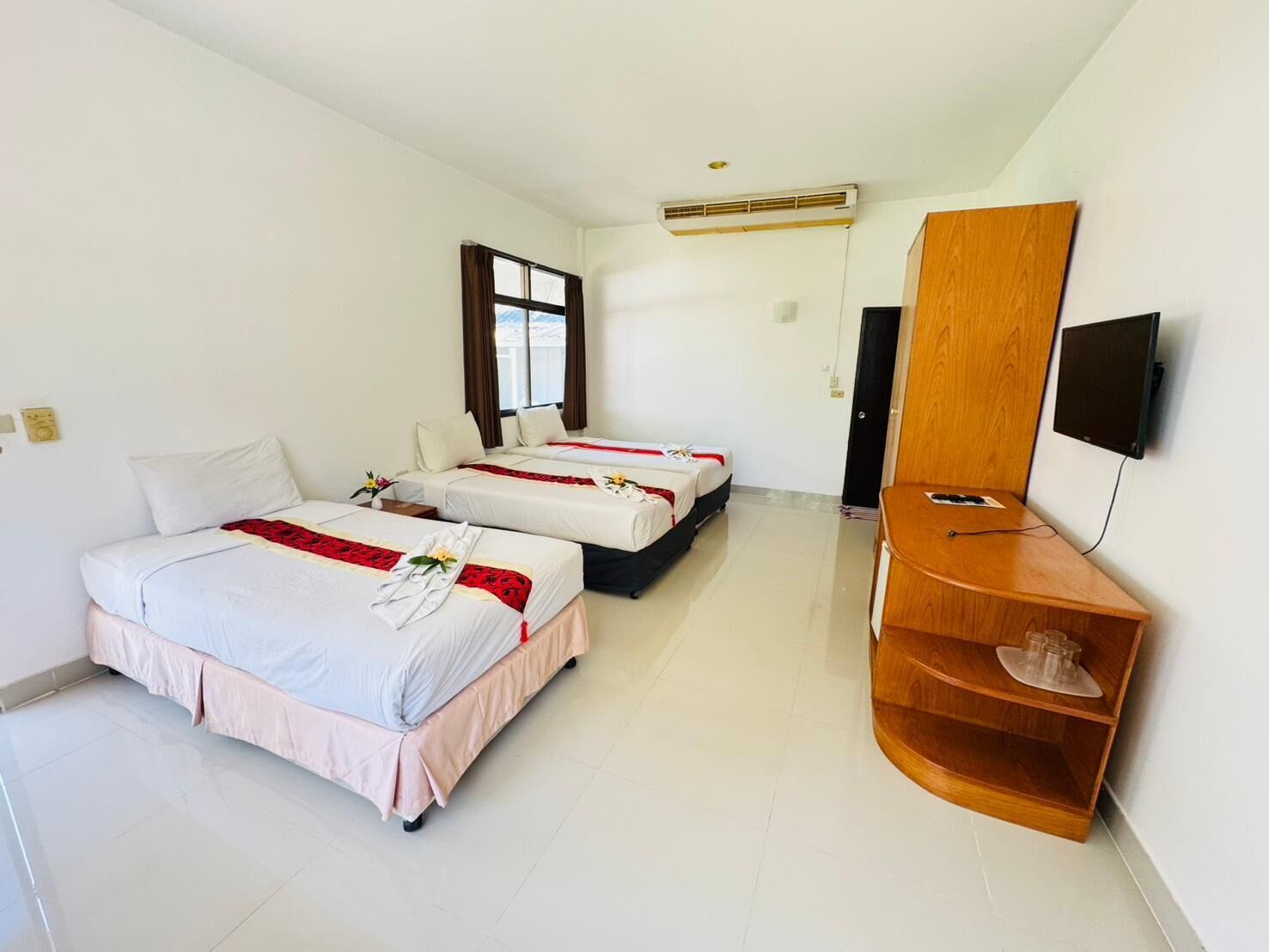 Habitación de hotel con dos camas, un televisor y un estante de madera.