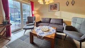 Ett vardagsrum med en soffa, två fåtöljer, ett soffbord och en kristallkrona.