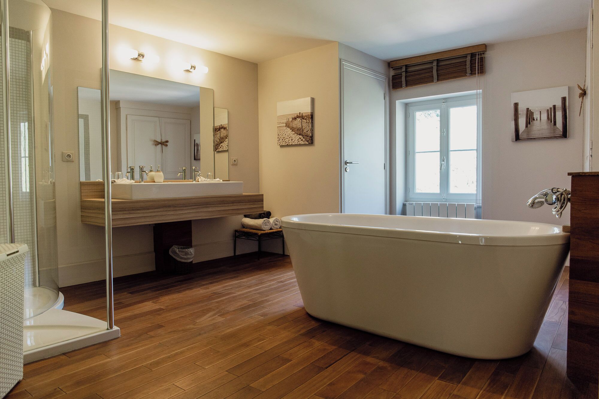 A bathroom with a freestanding bathtub, a glass shower enclosure, a vanity with a mirror, and a window providing natural light.