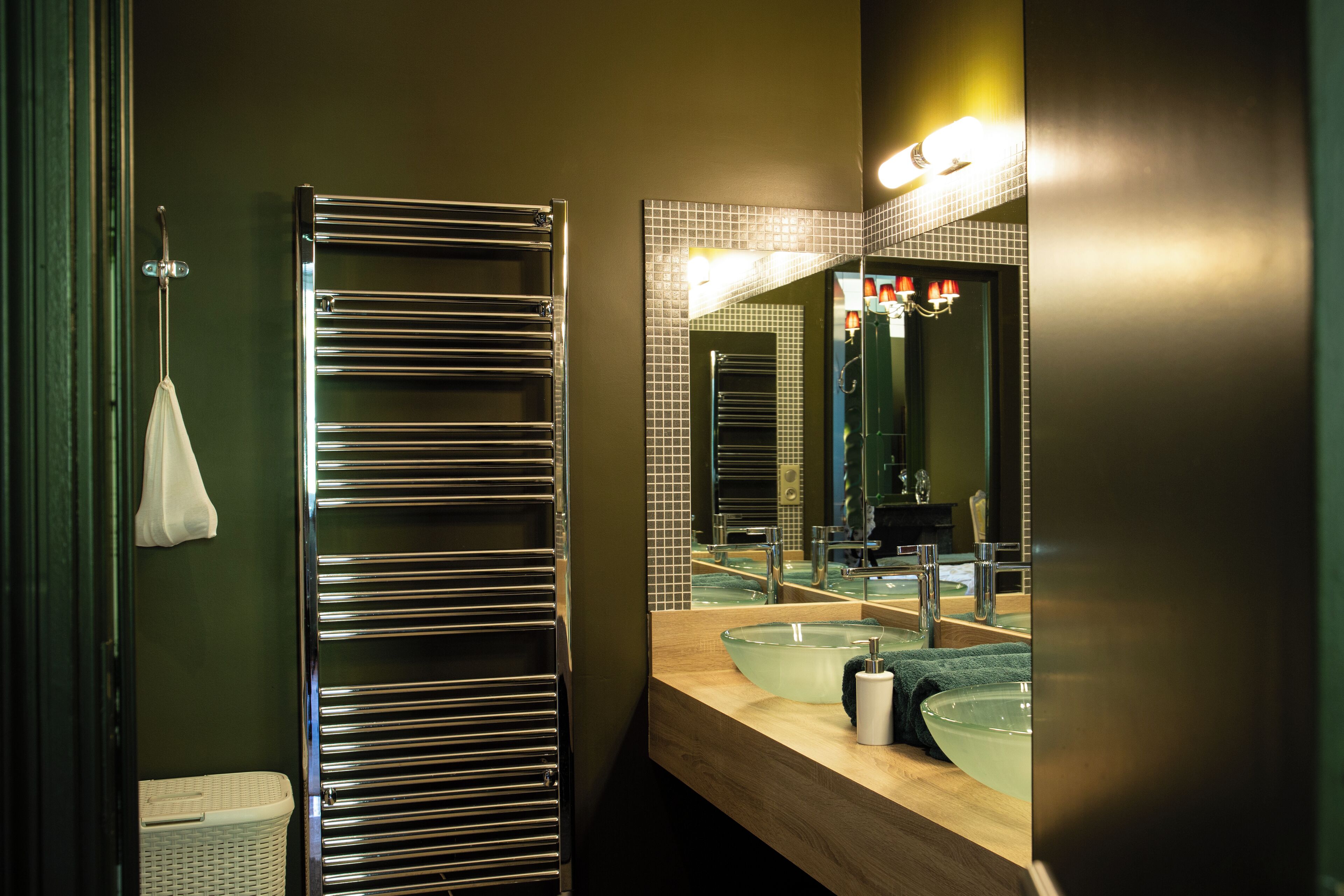 A modern bathroom with a large mirror, two sinks, and a towel rack.