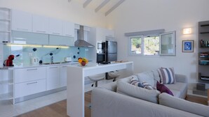 Una cucina moderna con mobili bianchi, forno integrato e microonde. C'è un'area pranzo con un tavolo bianco e un divano.