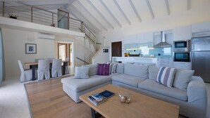 Un soggiorno moderno con un divano grigio, un tavolino in legno e una scala che conduce a un piano superiore.