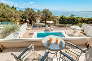 A rooftop pool area with a view of the sea, a table with drinks, and lounge chairs. - Villa Stavroula in Mparmpati (Corfu)
