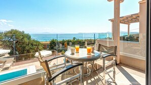 A balcony with a table and chairs, overlooking a pool and a scenic view of the sea. - Villa Stavroula in Mparmpati (Corfu)