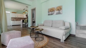 A living room with a sofa, two side tables, a patterned rug, and a painting on the wall. - Villa Stavroula in Mparmpati (Corfu)