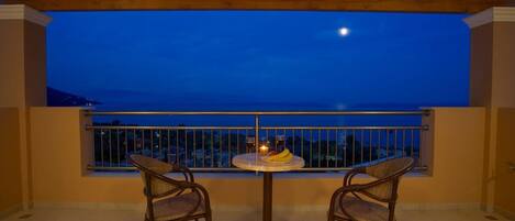Un balcon avec deux fauteuils en osier et une petite table ronde, offrant une vue panoramique.