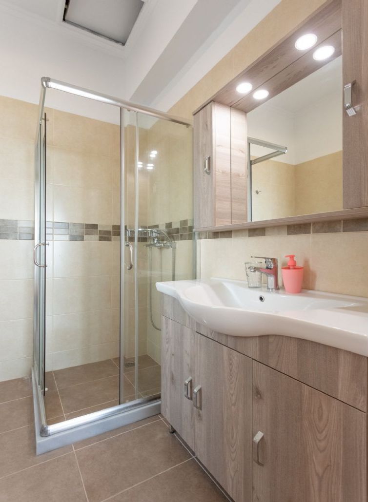 Une salle de bain moderne avec une douche à parois de verre, un lavabo blanc et des meubles en bois.