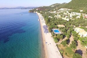 Vista aérea de una zona costera con playa, piscina y edificios residenciales.