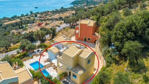 A coastal residential area with a pool, a red building, and a view of the sea. - Villa Sequoia Yellow (Corfu)