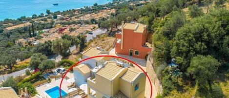 A coastal residential area with a pool, a red building, and a view of the sea.
