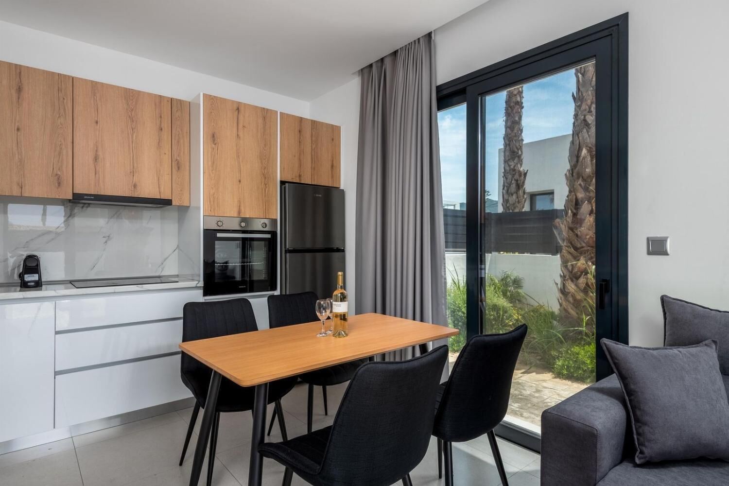 A modern kitchen with wooden cabinets, a black refrigerator, and a dining area with a table and chairs.