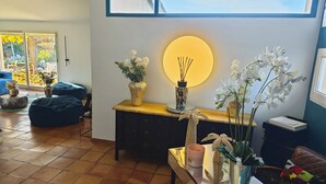 A living room with a large window, a round wall light, and various decorative items including vases and plants. - 6-hectare estate classified as a Grand Site de France concors Sainte Victoire (Jouques)