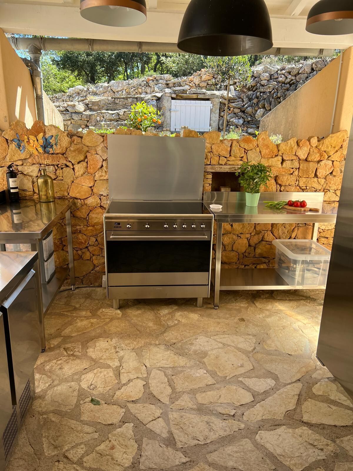 Cocina compacta con horno integrado, plancha y un fondo de pared de piedra.