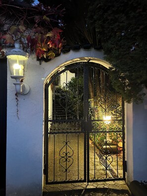 A gated entrance with a wrought iron gate and a wall-mounted light fixture. - Family apartment in the countryside. Private Garden & Sauna (Meckenbeuren)