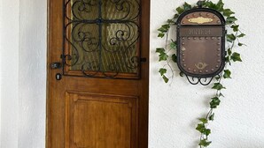 Eine Holztür mit dekorativem Metallgitter und einem Briefkasten mit der Aufschrift 'BRIEF', die an einer mit Efeu bewachsenen Mauer befestigt ist.