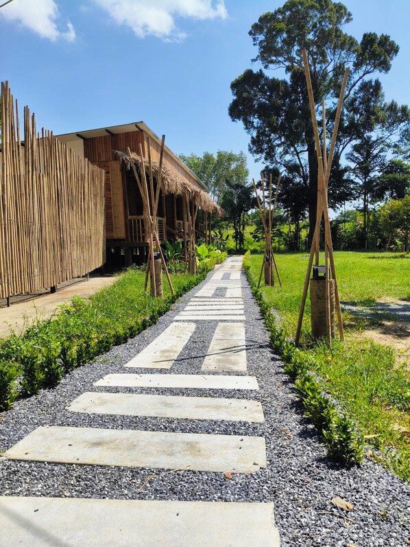 A pathway leading to a building with a thatched roof, surrounded by greenery and trees. - Painon Resort KohLanta (Ko Lanta)