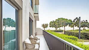 A balcony with wicker furniture and a view of a landscaped garden. - 3BR Family Residence w/ Distant Sea View and Assistant Room, Near to Beach (Fujairah)