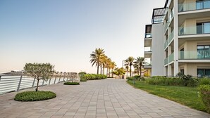 A paved walkway with palm trees and a building with balconies. - 3BR Family Residence w/ Distant Sea View and Assistant Room, Near to Beach (Fujairah)