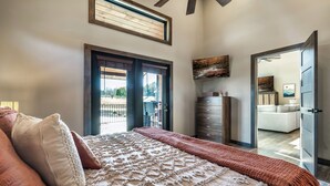 A bedroom with a large bed, a dresser, and a painting on the wall.