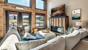 Un salón espacioso con un ventanal grande, televisor y chimenea.